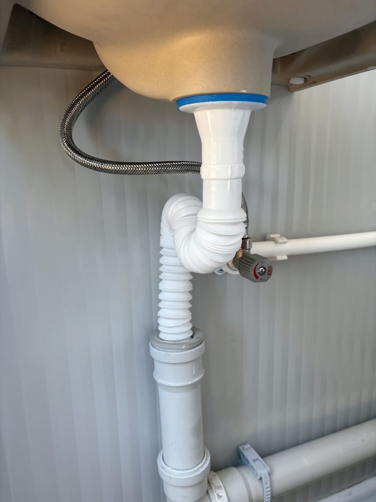 Close-up van leidingwerk bij wastafel in een mobiele toilet unit
