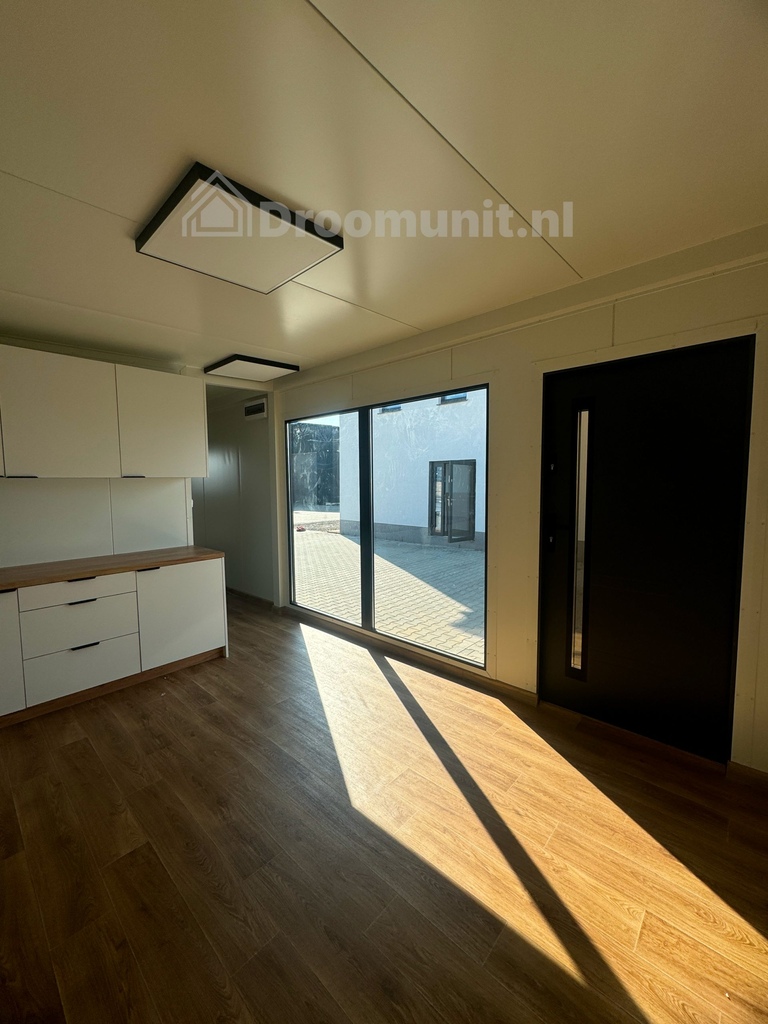 Leefruimte met keuken, kozijn en voordeur in luxe mobiele prefab woonunit Emmy met 1 slaapkamer, afmeting 900x300
