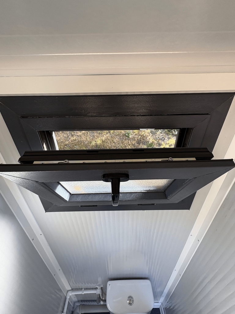 Geopend kiepraam aan de binnenzijde van een mobiele toilet unit