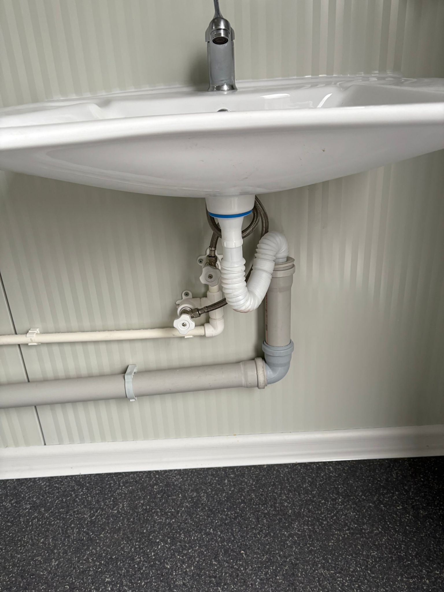 Leidingwerk onder wasbak in mobiele MIVA toiletunit