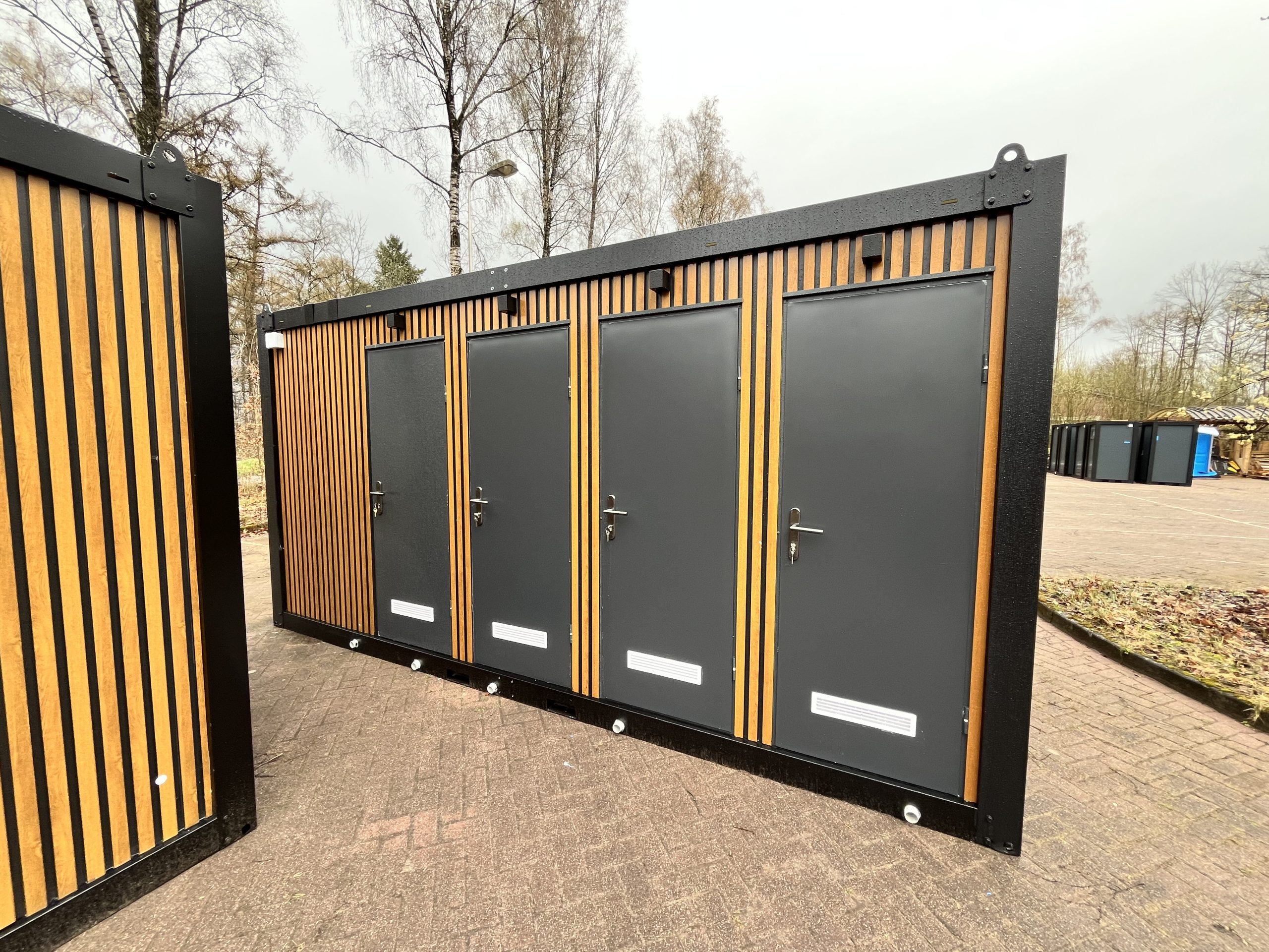 Doucheruimtes in maatwerk sanitairgebouw met gesloten deuren en nette afwerking