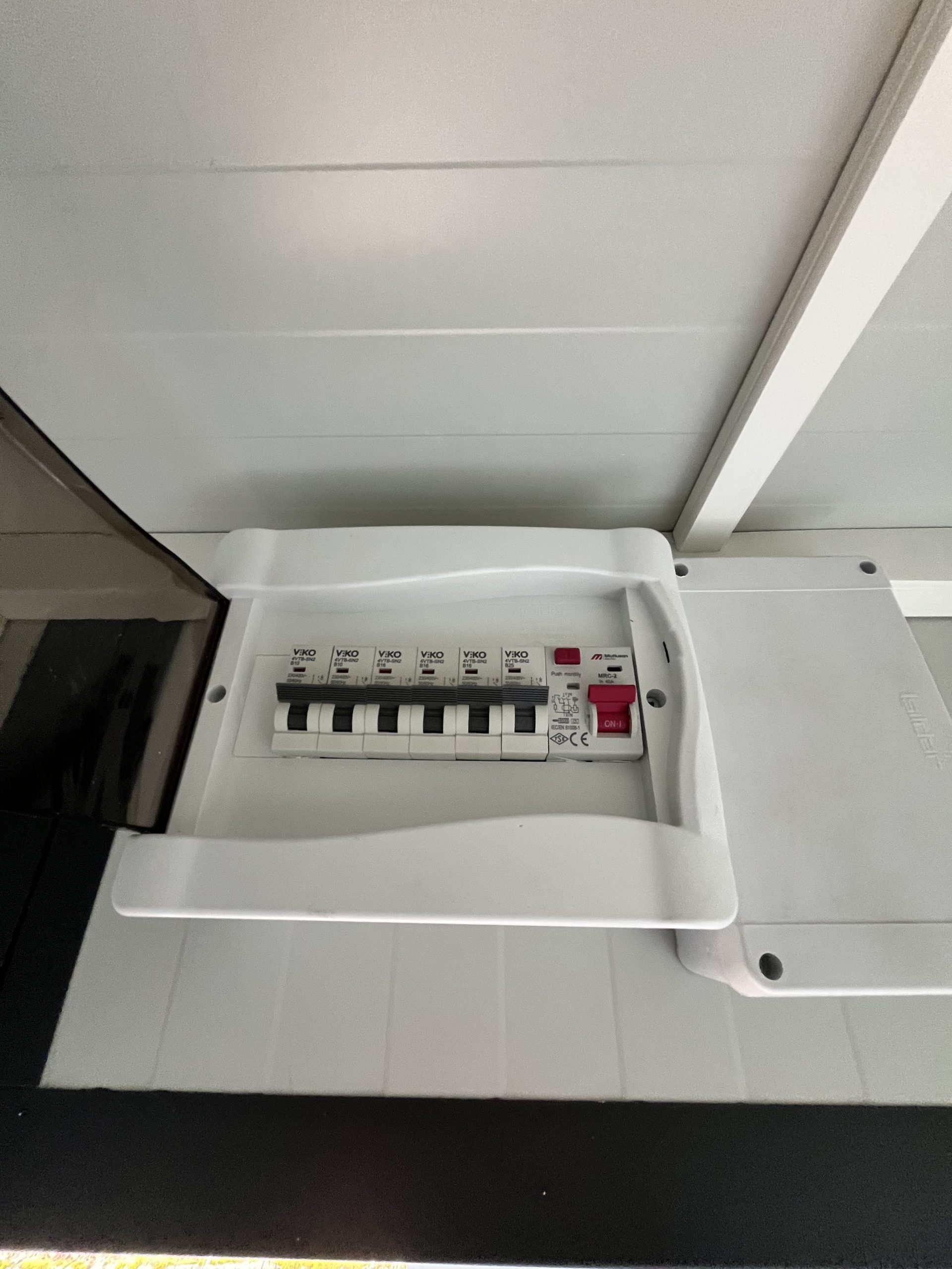 Geopende groepenkast in maatwerk sanitairgebouw met zicht op elektrische installatie en bekabeling