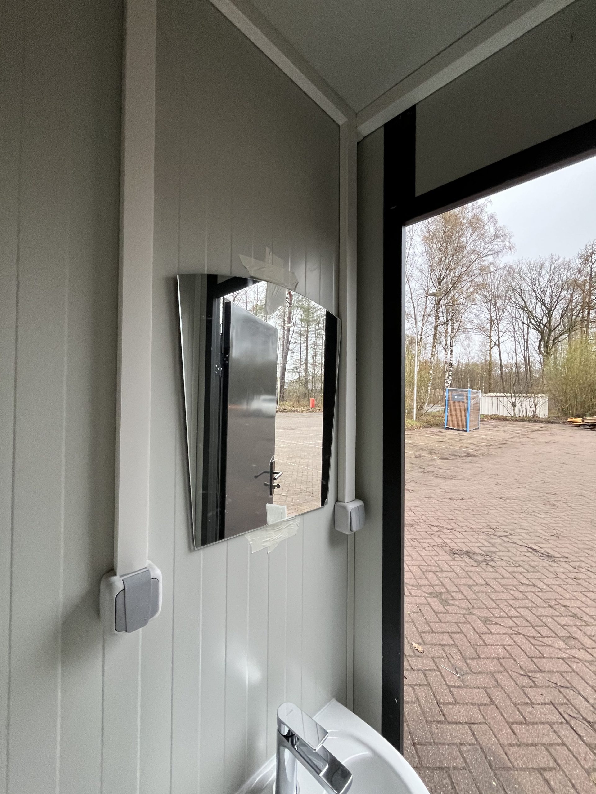 Spiegel in maatwerk sanitairgebouw met strakke afwerking en functioneel design