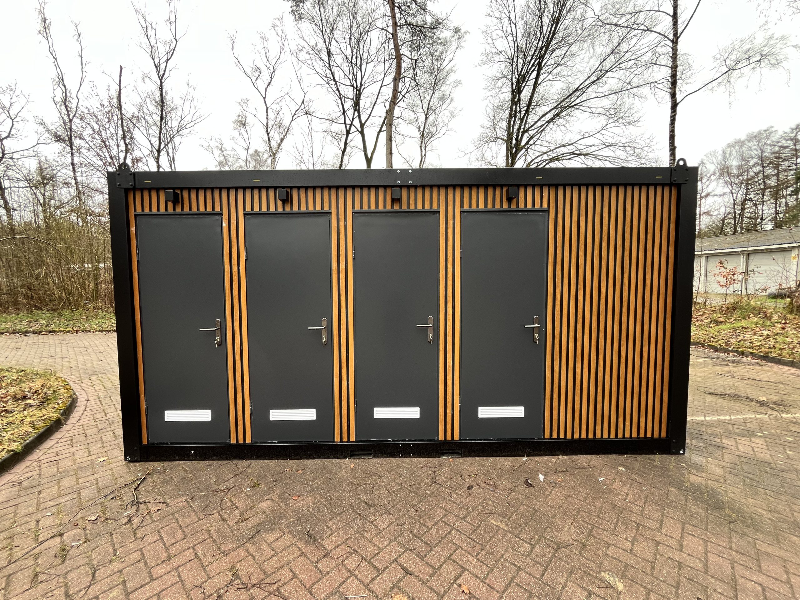 Vooraanzicht van maatwerk sanitairgebouw met moderne uitstraling en toegangsdeuren