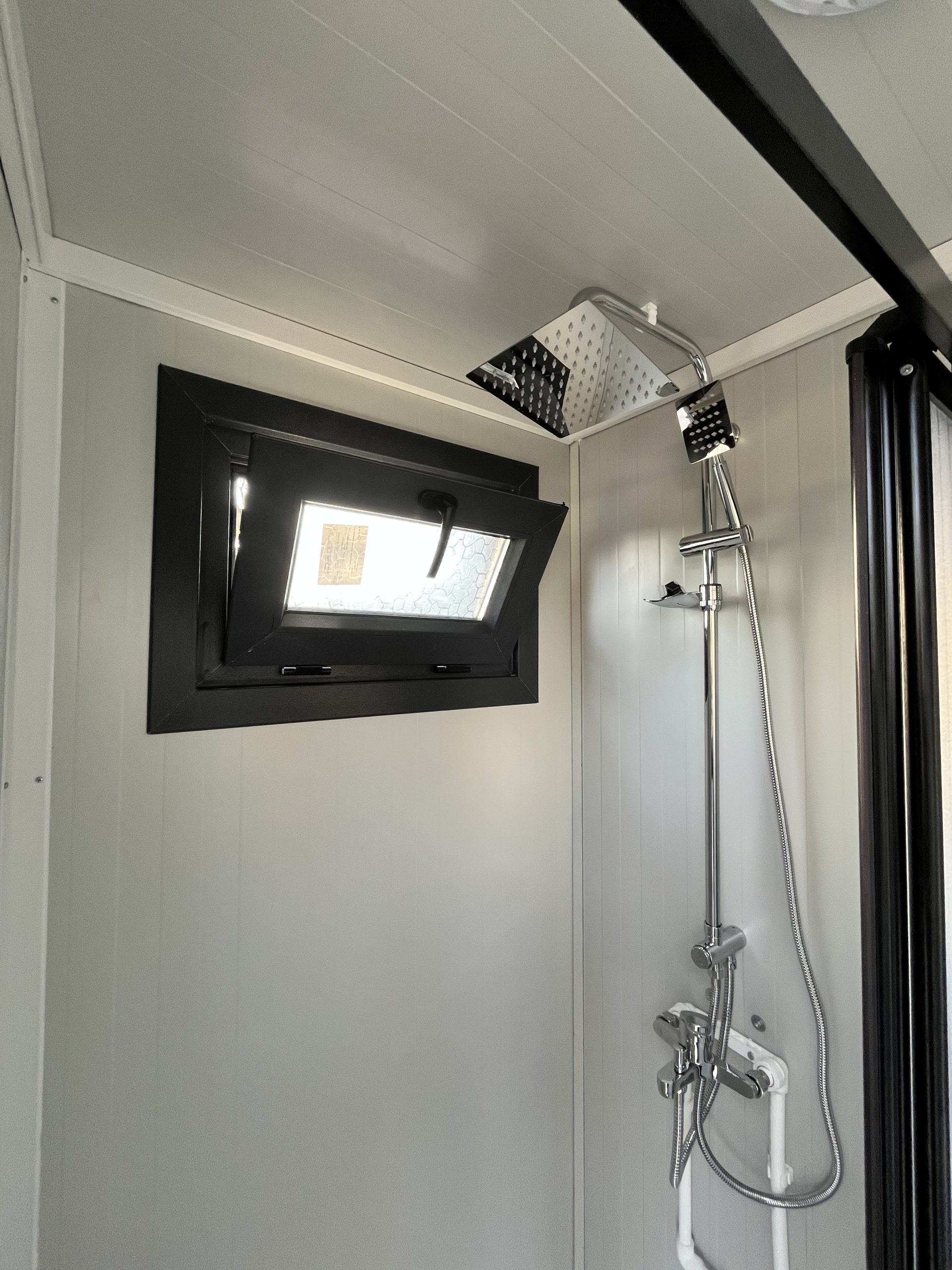 Draaikiepraam in doucheruimte van mobiele badkamer unit met 4 ruimtes