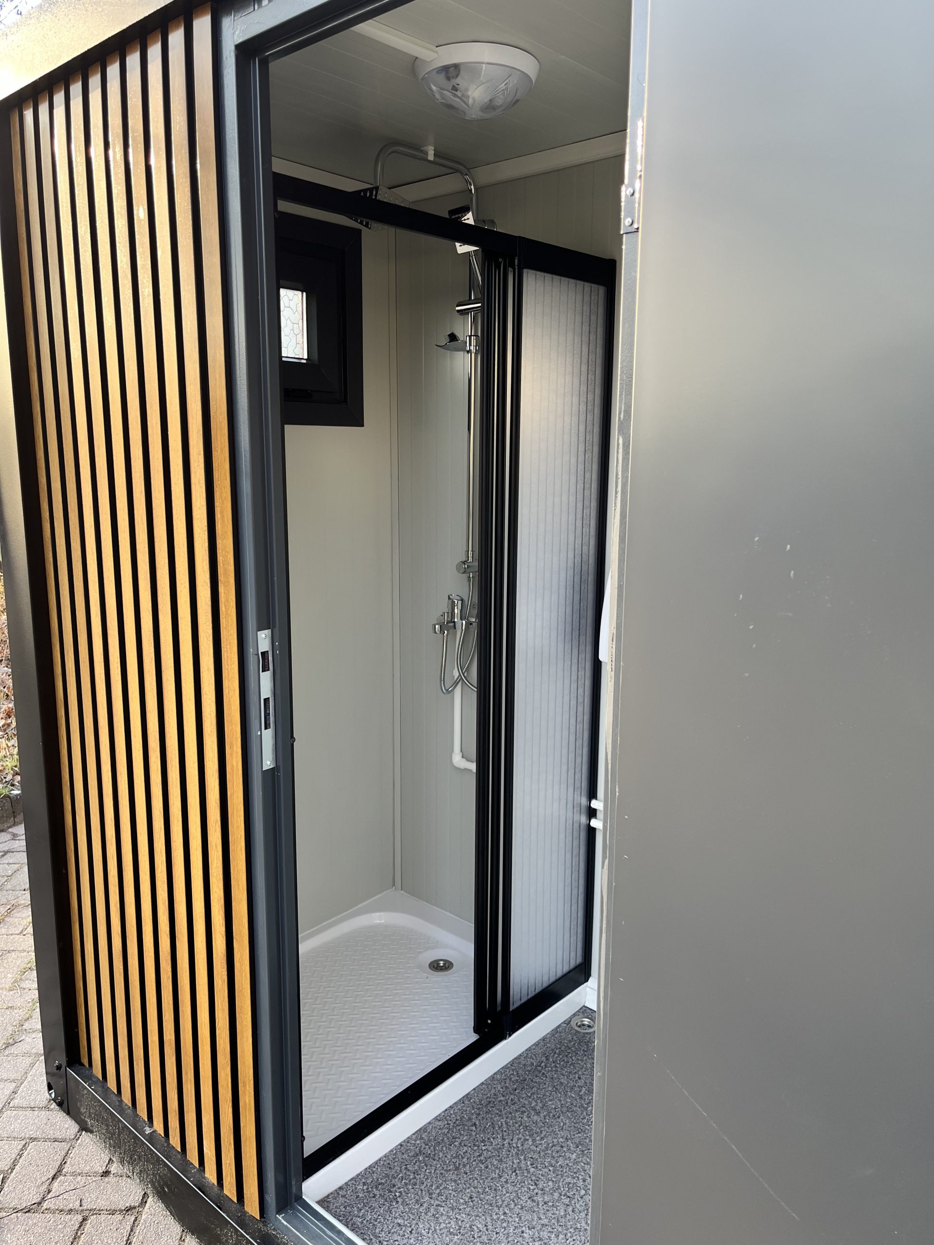 Inkijk in doucheruimte van mobiele badkamer unit met 4 ruimtes