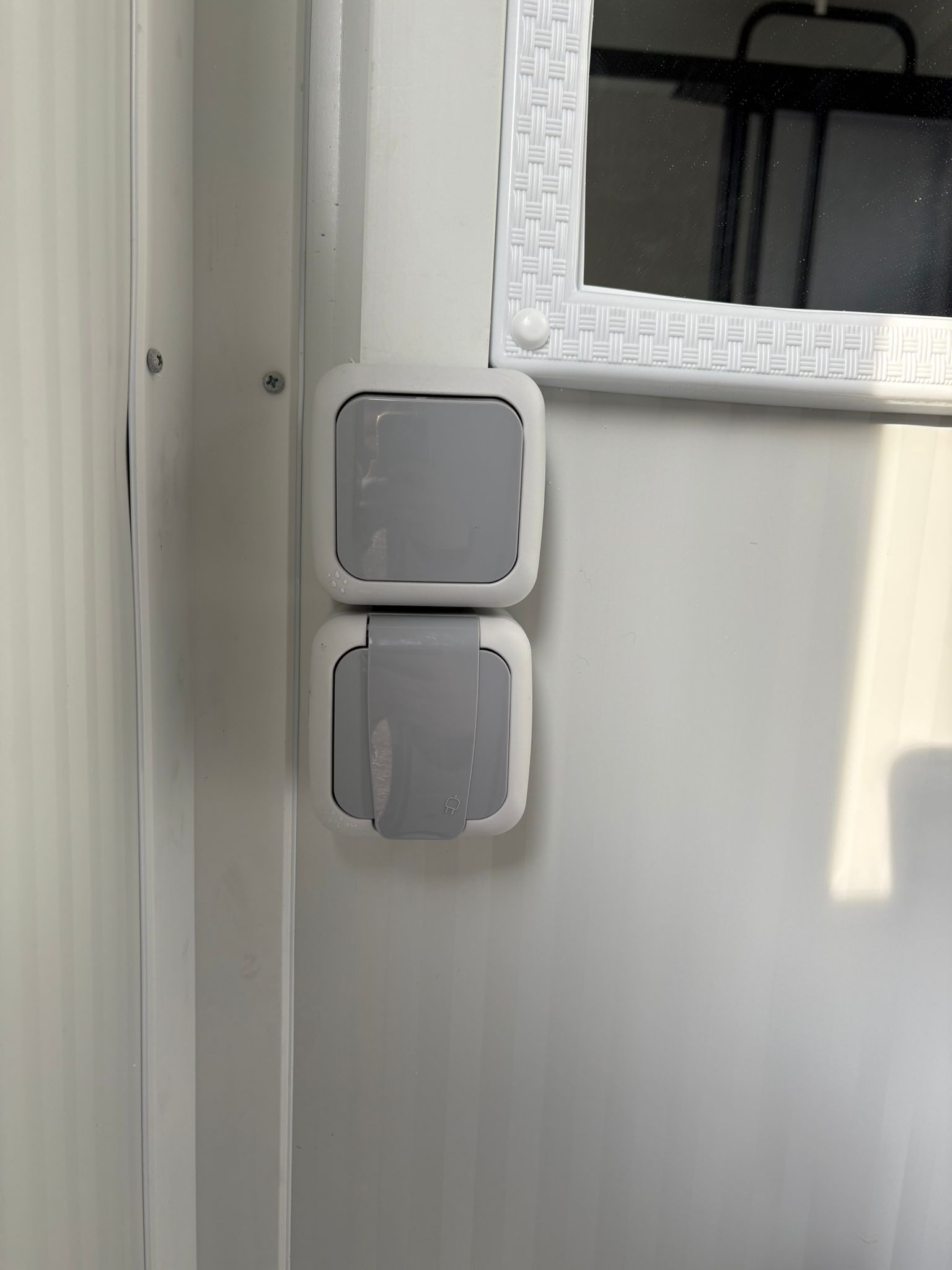 Lichtschakelaar en wandcontactdoos van een doucheunit met omkleedruimte.