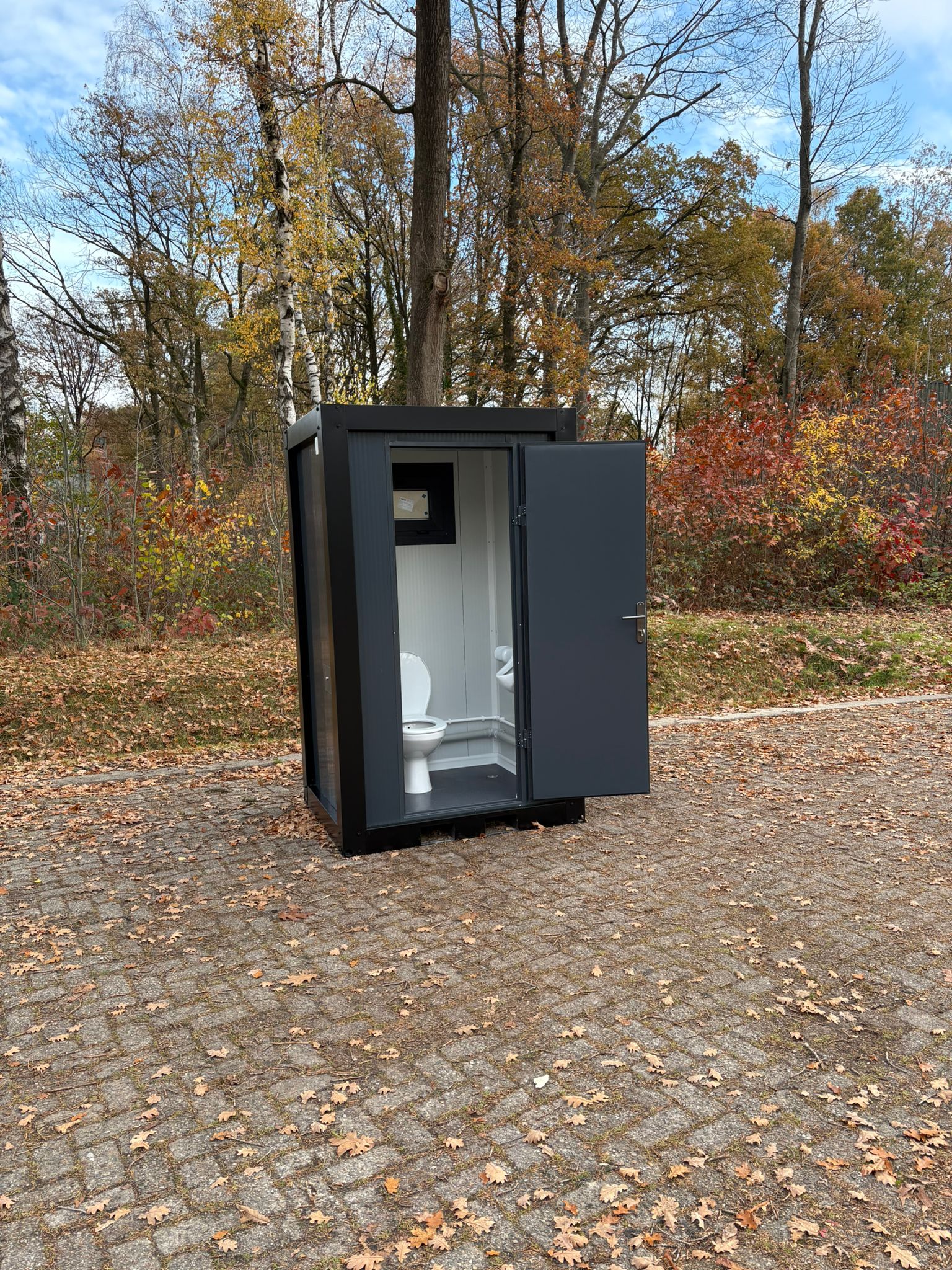 Zijkant single toilet unit met open deur en urinoir