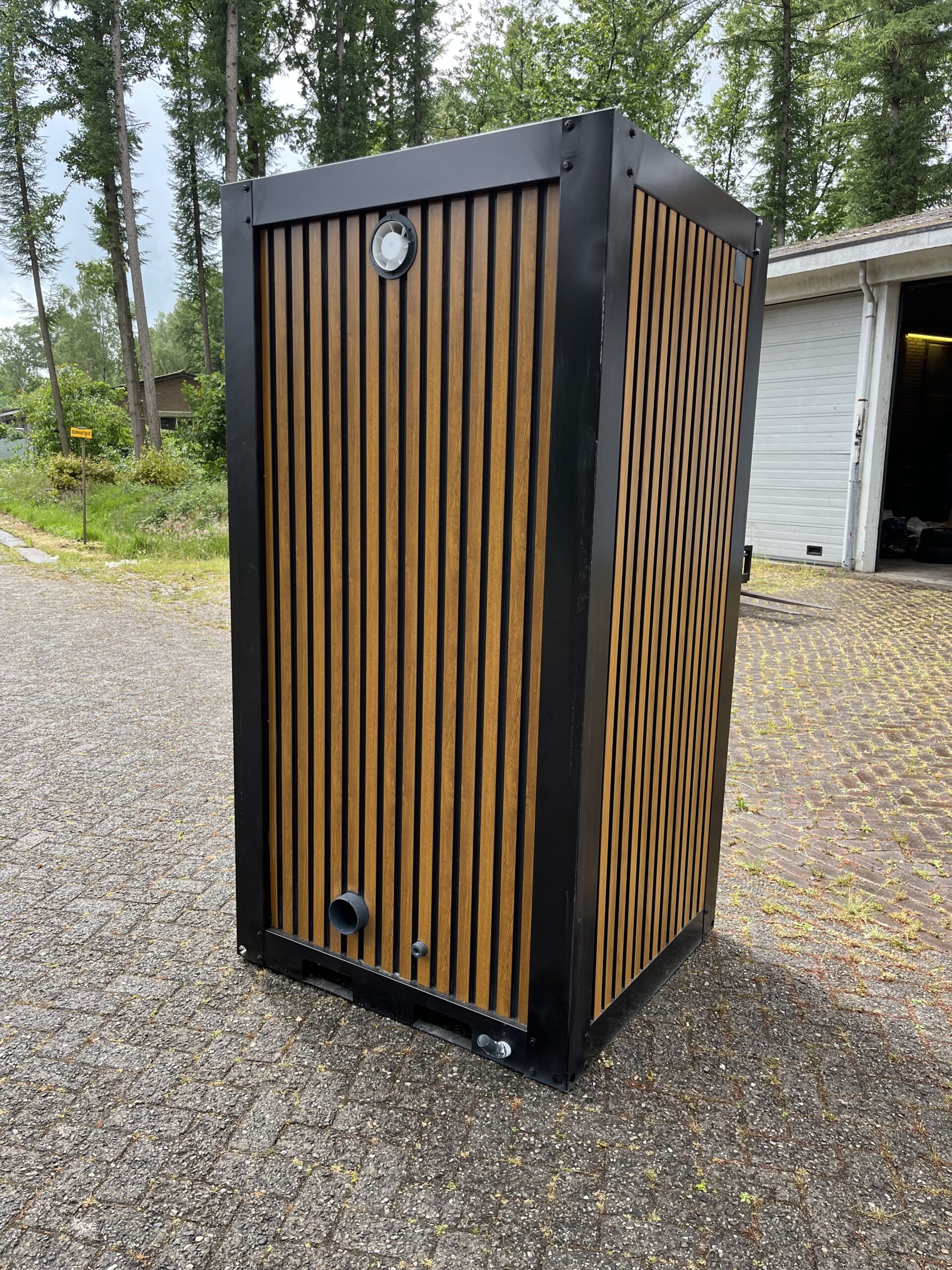 Achterzijde van een mobiele douchecabine unit met pvc houtlook afwerking