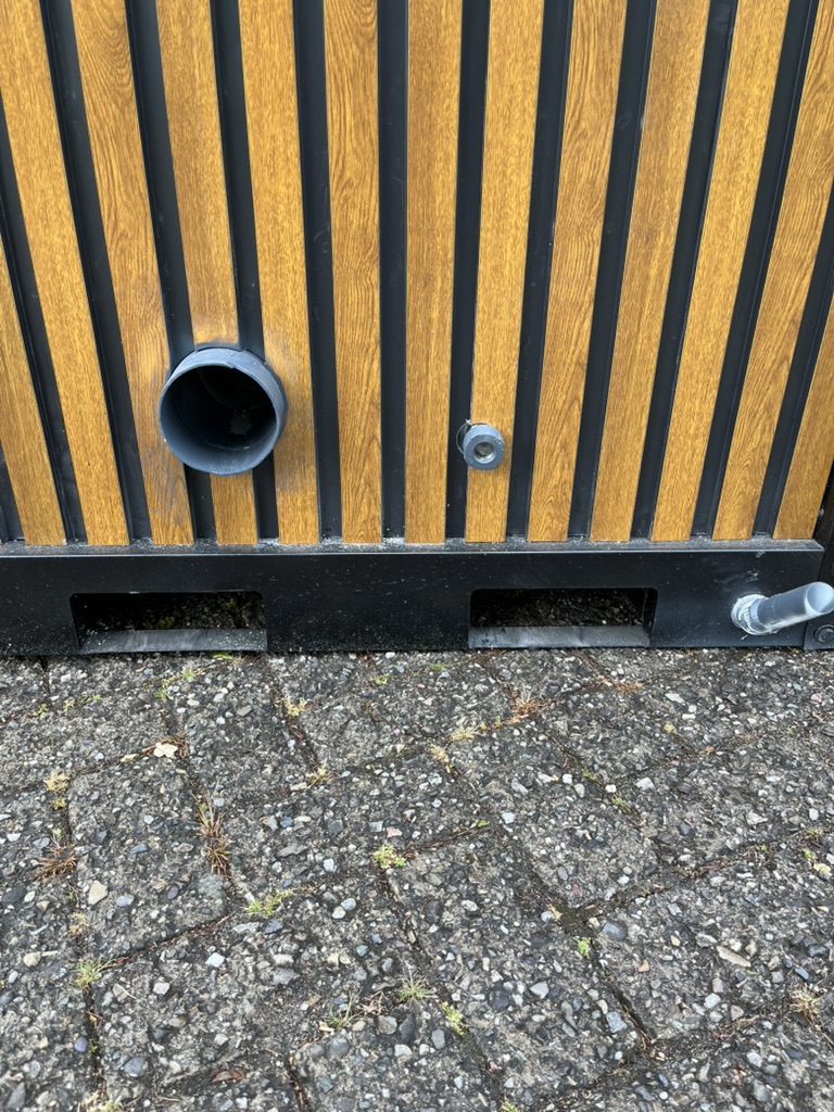 Achterzijde van een mobiele miva toilet unit met aansluitingen voor riool, afwatering en water