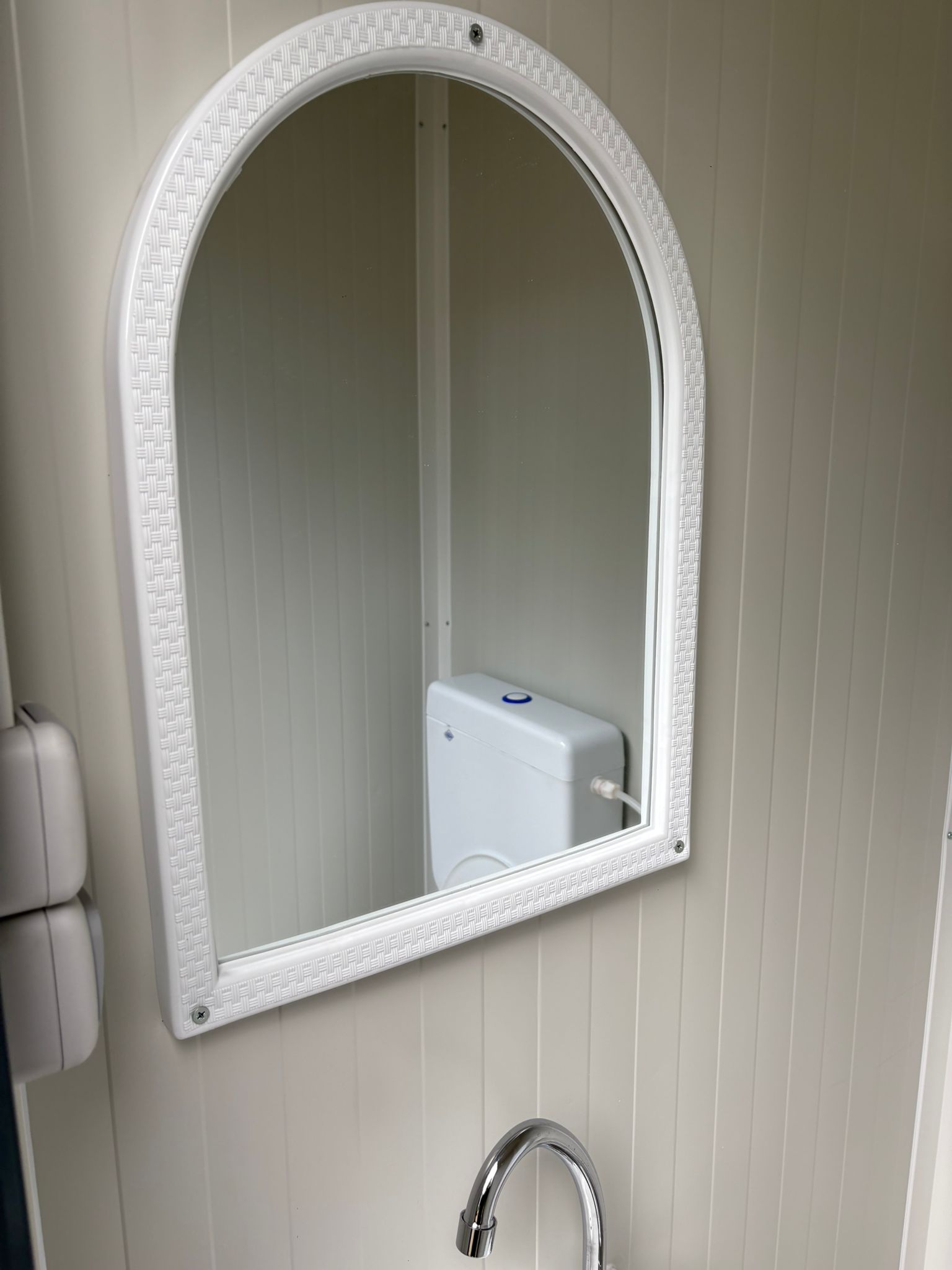 Binnenzijde van de toiletcabine in een mobiele wc- en douche unit met spiegel boven de wastafel